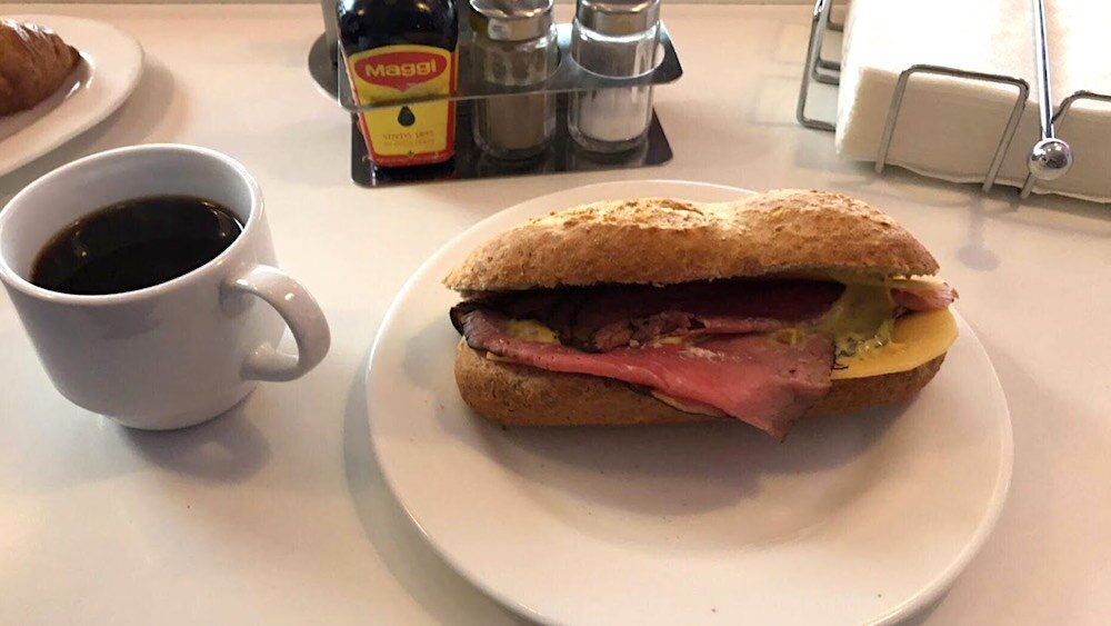 simple Dutch sandwich with brown bread, beef, cheese and a cup of coffee on a white table 