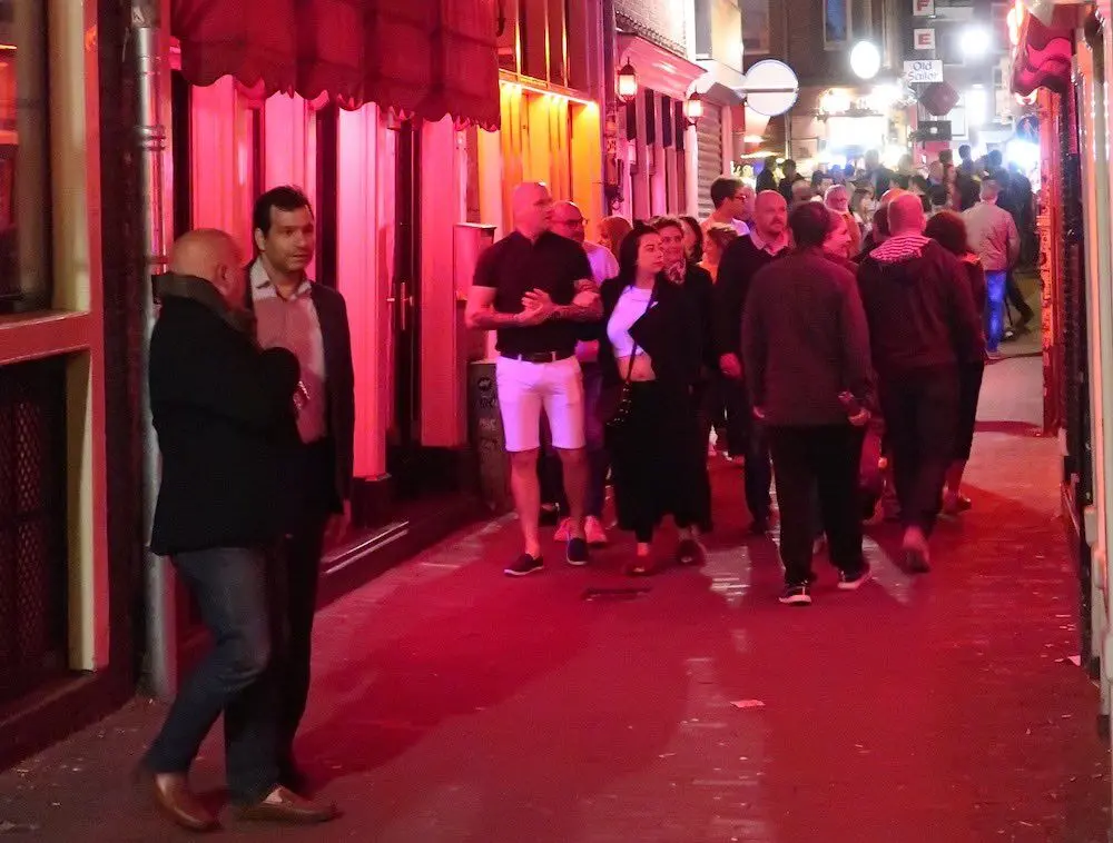 tourists in De Wallen of Amsterdam looking at window brothels