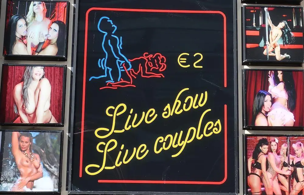 Werbung für eine Peepshow in Amsterdam mit unbekleideten Stripperinnen und dem Preis von 2 Euro für eine Live-Show