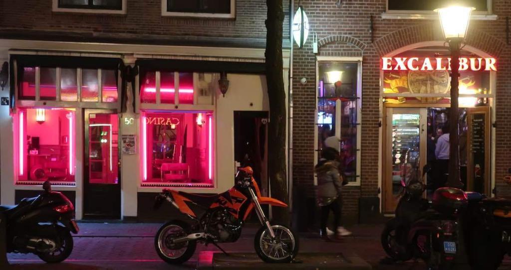Fensterbordell neben dem Cafe Excalibur bei Nacht im Amsterdamer Rotlichtviertel