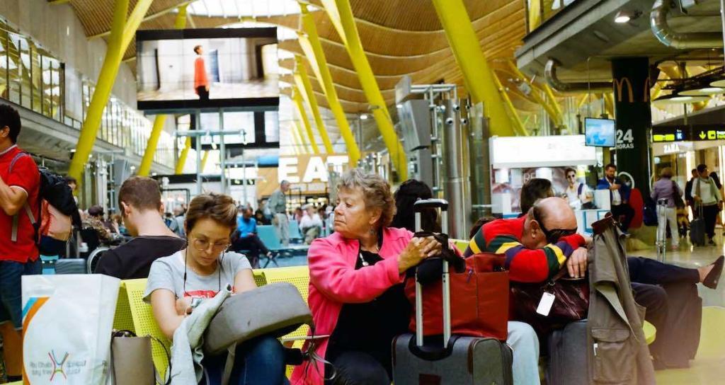 busy airport with people waiting and sitting next to each other