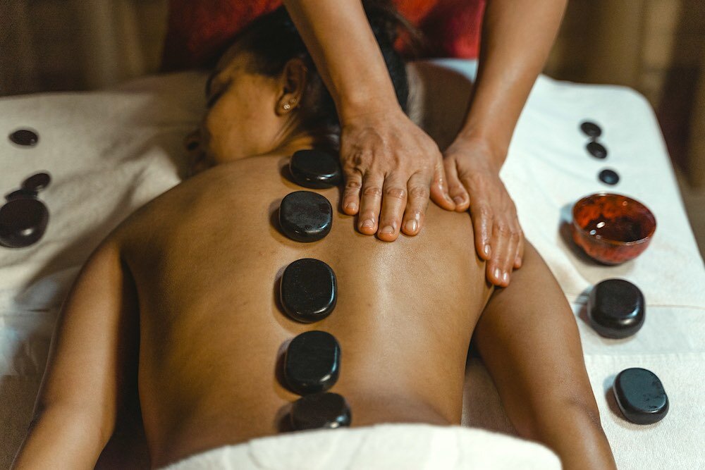 a female client gets a hot stone massage while being massaged by a woman
